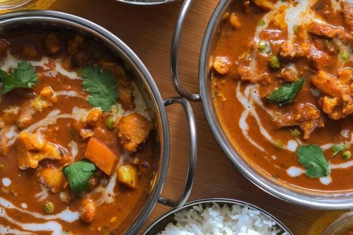 Curry dishes and rice served in steel karahis